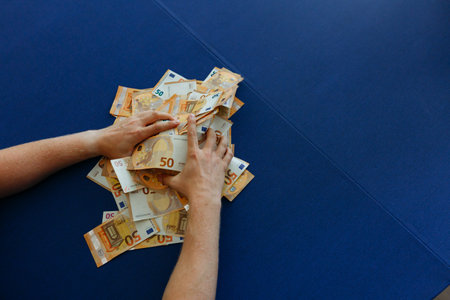 upper view of sitting man counting money on the table