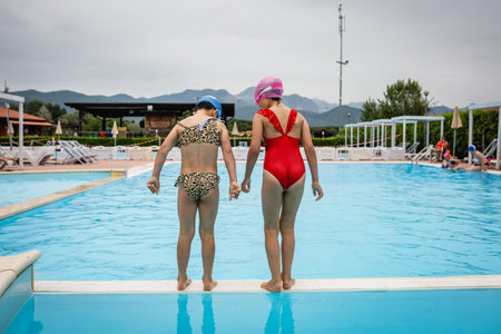 rear view of two girls preparing to jump in the water in the pool outdoorsの写真素材