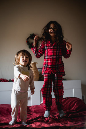 two children jumping on the bed at home in pyjamasの写真素材