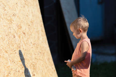 A little boy with blond hair looks in front of him.The kid is thinking about what to do.The boy plays a builder-painterの写真素材