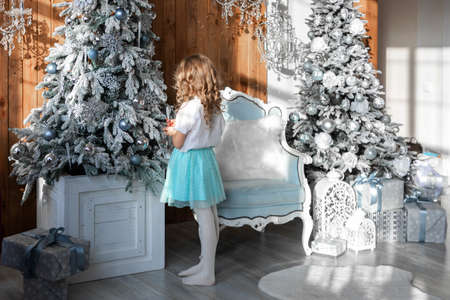 The girl stands with her back and decorates the Christmas treeの写真素材