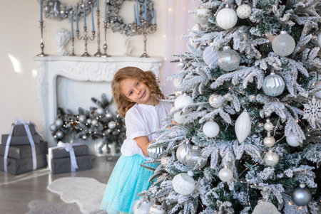 A girl looks out from behind a beautiful Christmas treeの写真素材