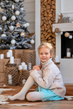 A child on the background of a Christmas tree, gift boxes and a decorative fireplaceの写真素材