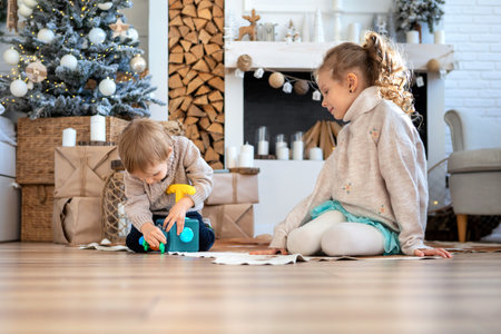 A boy and a girl are passionate about gifts on the background of a decorative fireplaceの写真素材