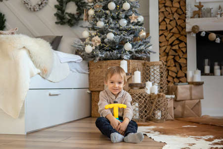 A little boy is playing on the floor in a warm sweater and pantsの写真素材
