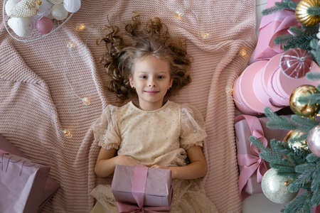 Top view of a lying girl in a beautiful dress.The girl has a gift in her handsの写真素材