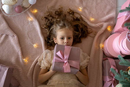 Top view of a lying girl in a beautiful dress.The girl has a gift in her handsの写真素材