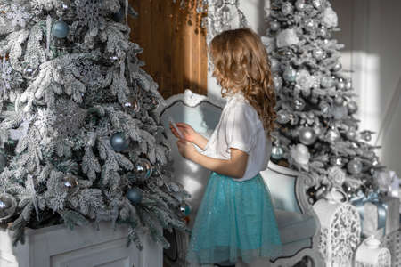 The girl stands with her back and decorates the Christmas treeの写真素材