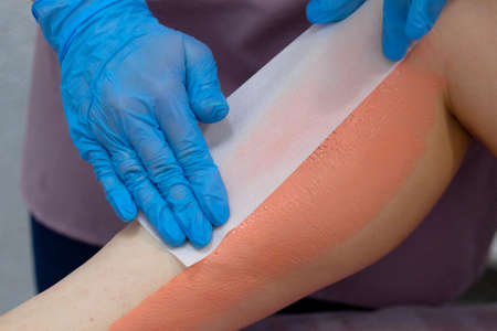 The master removes the wax with the help of special bandage stripsの写真素材
