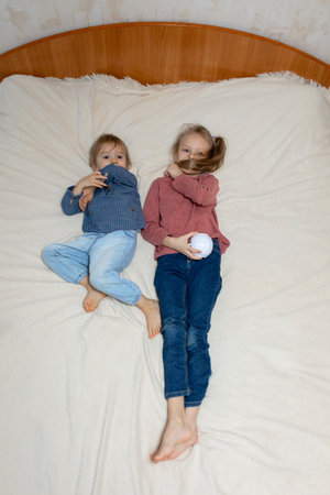 A boy and a girl are lying on the bed with a projectorの写真素材