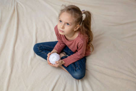 The girl is sitting on the bed and looking at something through the projectorの写真素材
