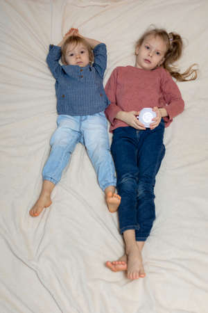 A boy and a girl are lying on the bed with a projectorの写真素材