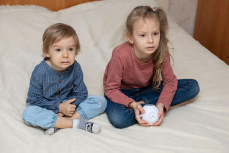 The brother and sister are closely and enthusiastically watching something