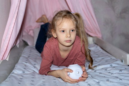 The girl has a small portable projector in her hands for watching moviesの写真素材