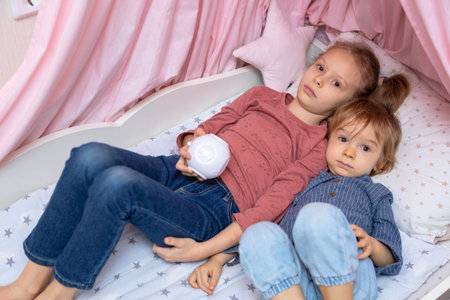 A boy and a girl are lying on the bed with a projectorの写真素材