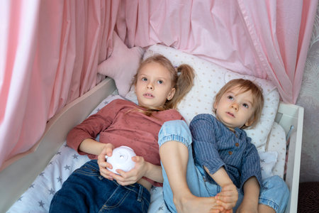 A boy and a girl are lying on the bed with a projectorの写真素材