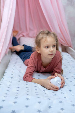 The girl has a small portable projector in her hands for watching moviesの写真素材