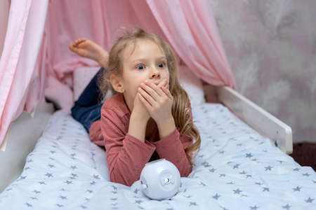 The girl has a small portable projector in her hands for watching moviesの写真素材