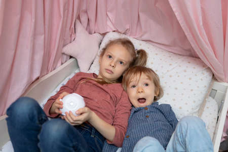 A boy and a girl are lying on the bed with a projectorの写真素材