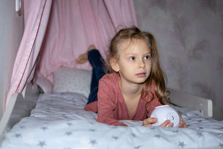 The girl has a small portable projector in her hands for watching moviesの写真素材