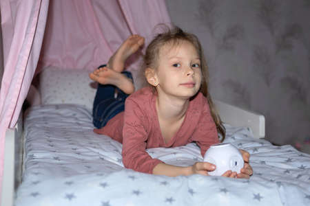 The girl has a small portable projector in her hands for watching moviesの写真素材