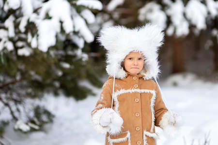 A girl in a funny fur hat with bambos in a snowy forestの写真素材
