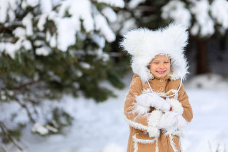 A girl in a funny fur hat with bambos in a snowy forestの写真素材