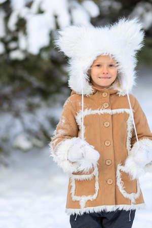 A girl in a funny fur hat with bambos in a snowy forestの写真素材