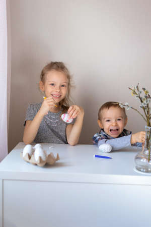 Brother and sister paint decorative Easter eggs with felt-tip pens