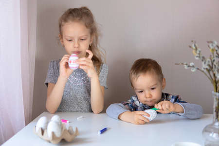Brother and sister paint decorative Easter eggs with felt-tip pensの写真素材
