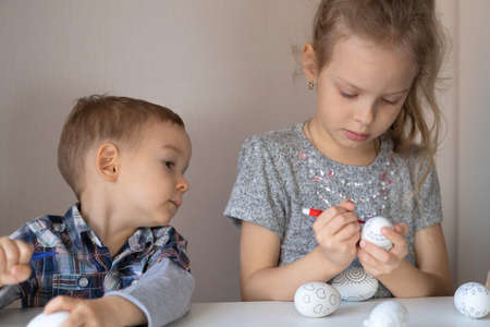 Brother and sister paint decorative Easter eggs with felt-tip pensの写真素材