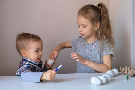 Brother and sister paint decorative Easter eggs with felt-tip pensの写真素材