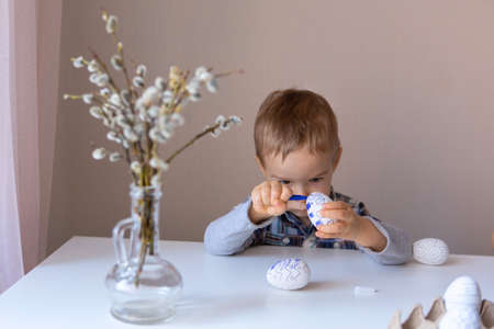 The boy paints decorative eggs for Easter with felt-tip pensの写真素材