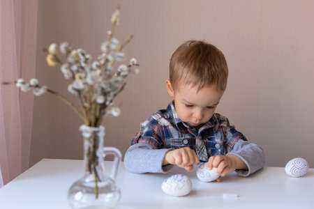 The boy paints decorative eggs for Easter with felt-tip pensの写真素材