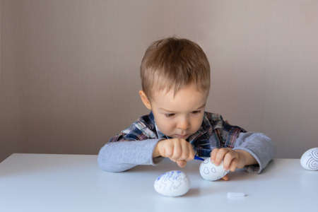 The boy paints decorative eggs for Easter with felt-tip pensの写真素材