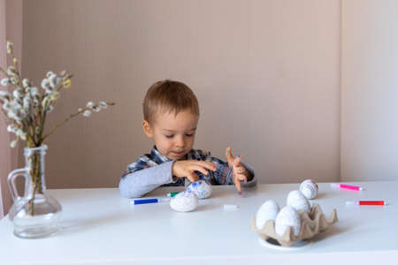 The boy paints decorative eggs for Easter with felt-tip pensの写真素材