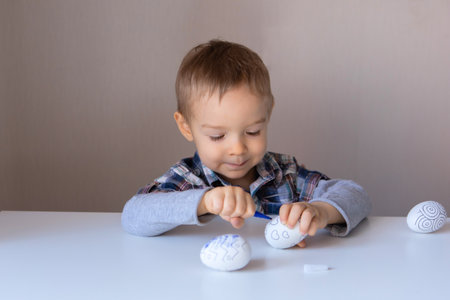 The boy paints decorative eggs for Easter with felt-tip pensの写真素材