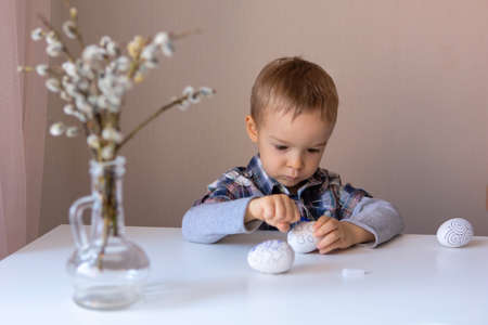 The boy paints decorative eggs for Easter with felt-tip pensの写真素材