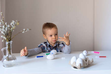 The boy paints decorative eggs for Easter with felt-tip pensの写真素材