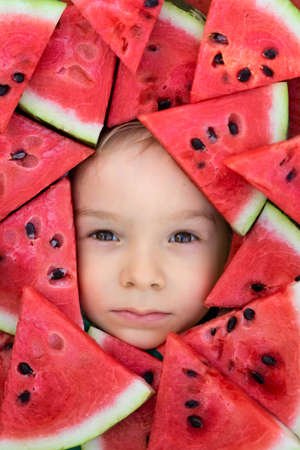 A boy framed by triangular pieces of watermelon.Cute portrait of a babyの写真素材