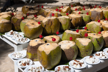 There are a lot of fresh coconuts on the table with the top cut offの写真素材