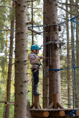 A child wearing a helmet and safety ropes will pass rope trails in a sports parkの写真素材