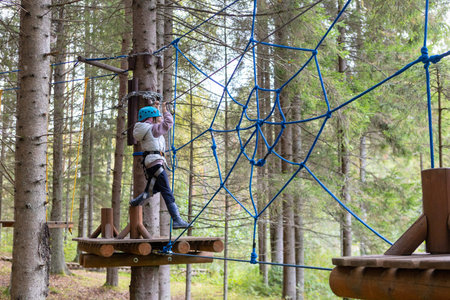 A child wearing a helmet and safety ropes will pass rope trails in a sports parkの写真素材