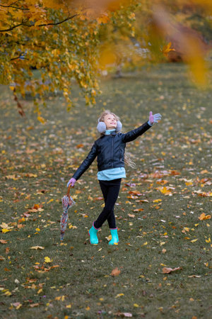 A girl in rubber boots and with an umbrella on a background of yellowed woodの写真素材