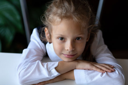 A girl is sitting at a table with her head in her hands.Portrait of a girl