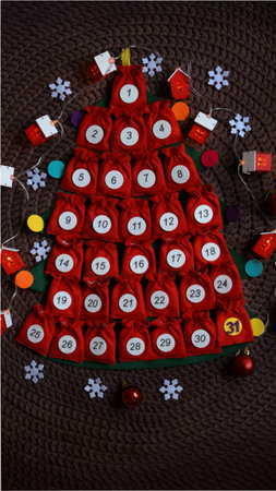 Advent calendar in the form of a felt Christmas tree with red Velcro pouches.の写真素材