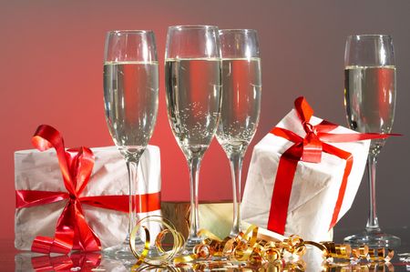 Glasses of champagne, gifts with red tapes and bowsの写真素材