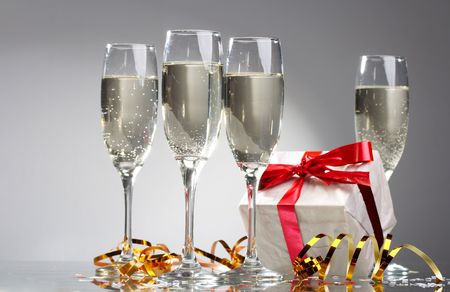 Glasses of champagne, gifts with red tapes and bowsの写真素材