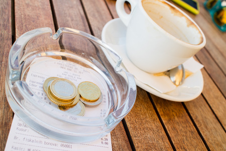 coffee with few coins and bill on wood tableの写真素材
