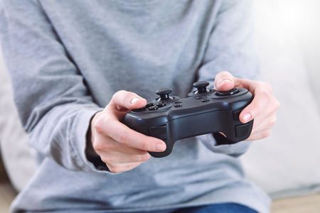 man holding a joystick controllers while playing a video games at homeの写真素材